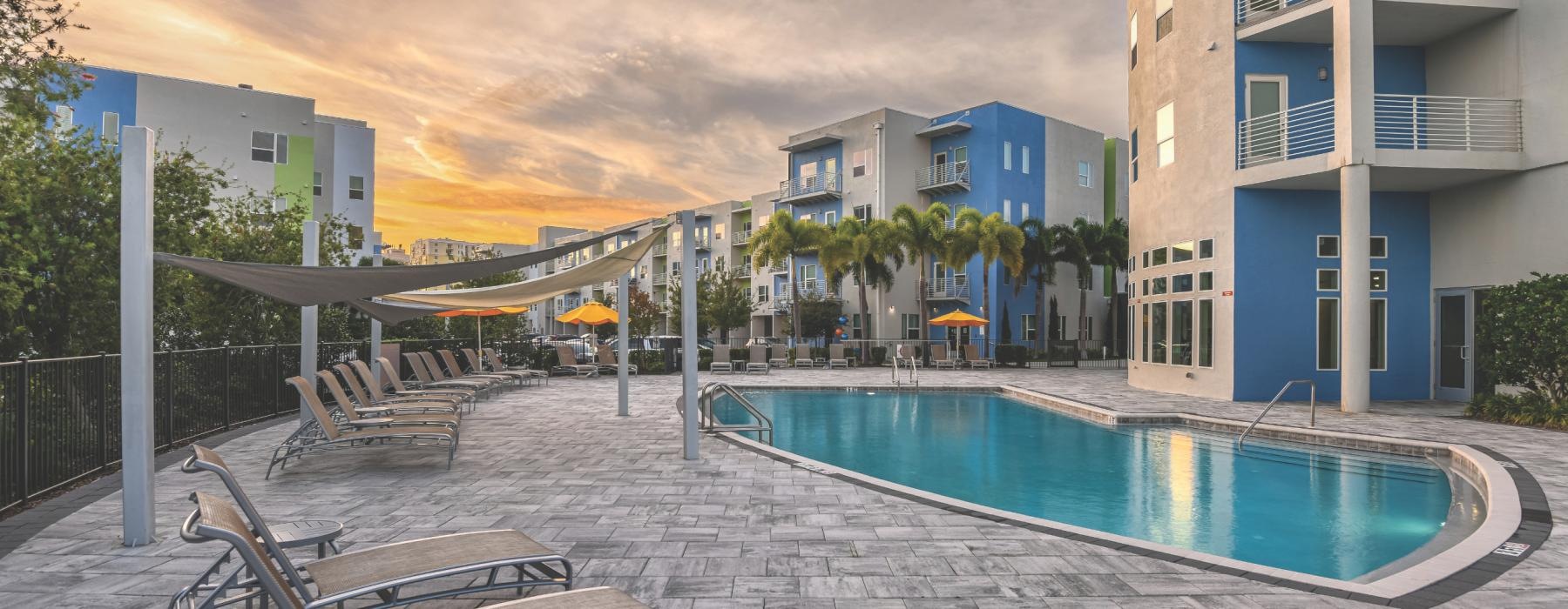 a pool with chairs and a table by it by a building